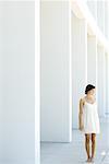 Woman in sundress standing outdoors in front of modern colonnade