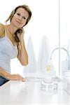 Woman standing by bathroom sink, smiling at camera