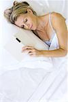 Woman asleep in bed with open book next to her