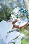 Woman holding glass sphere in hand, cropped view