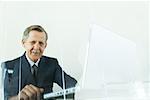 Businessman using laZSop computer, smiling at camera, low angle view