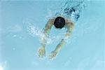 Homme nageant dans la piscine, tête baissée, les bras tendus devant lui