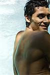 Homme en piscine, souriant par-dessus l'épaule à la caméra