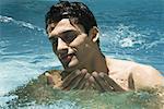 Man splashing in swimming pool, eyes closed, close-up