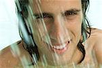 Man splashing in swimming pool, smiling at camera, close-up