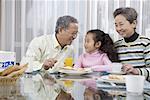 a girl and her grandma and grandpa taking breakfast