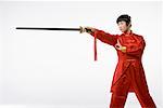 a woman in red dress practicing Chinese Kungfu with a sword