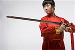 une femme en robe rouge pratiquant de kung fu chinois avec une épée