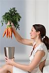 Woman Placing Bunch of Carrots into Container
