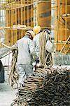 Travailleurs de la construction du câble porteur, barres de métal empilées en premier plan site