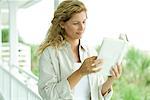 Woman standing on porch, reading book, close-up