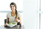 Teen girl eating salad, smiling at camera