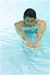 Man swimming in pool, arms out, high angle view