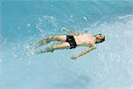 Homme flottant sur le dos dans la piscine, vue grand angle
