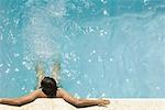 Man in swimming pool, holding on to edge, high angle view