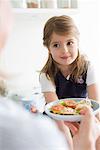 Mother handing plate to daughter