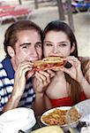Young adult couple eating sandwich