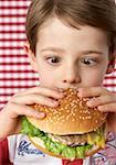 Garçon (4-5 ans) tenant un cheeseburger