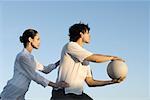 Couple together outdoors, man holding ball, woman holding man's hips