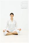 Woman sitting in lotus position, eyes closed