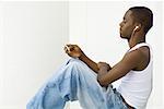 Teen boy sitting, listening to MP3 player, side view