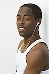 Teen boy listening to earphones, smiling at camera, portrait