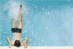 Homme tenant à bord de la piscine, coups de pieds, vue grand angle