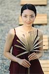 Woman holding dried palm leaf, smiling at camera