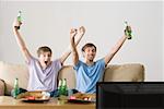 Two young men cheering at the tv
