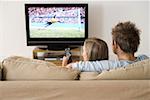 A young couple watching a football match on the tv