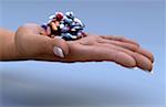 An open human palm holding a pile of pills.