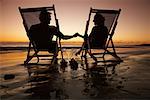 Couple assis dans des chaises de plage, sur la plage au coucher du soleil, Mexique