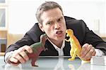 Homme d'affaires jouant avec des jouets dinosaures