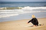 Surfeur accroupi sur la plage, Huntington Beach, Californie