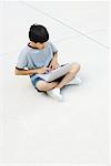 Boy sitting cross-legged on the ground, using laptop
