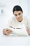 Man reading book, sitting at table