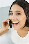 Woman using cell phone, looking at camera, laughing