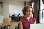 A woman sitting behind a laptop in a loft-style office.