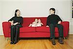 Parents sitting on a sofa with twin babies.