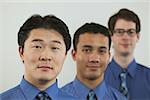 Studio portrait of three businessmen in blue shirts.