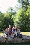 Portrait of a family of five sitting on a log.