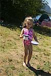 Young girl carrying food and drink at a campsite.