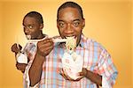 Twin teen boys eating noodles from cartons.