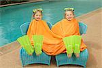 Young, twin girls share a towel poolside.