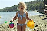 Jeune fille tenant des jouets de plage.