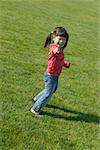 Young girl playing in grassy field.