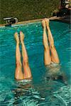 Two pairs of girls' legs pointing up out of a swimming pool.