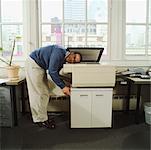 A man with his head in a copy machine.