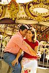 Hispanic couple in front of a carousel.