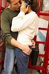 A young couple kissing in a phone booth.